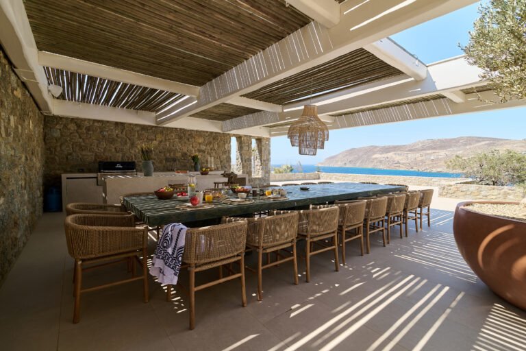 Long dining table under a shaded terrace at a villa in Mykonos
