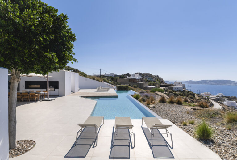 Infinity pool with sun loungers and an Aegean view at a villa in Mykonos